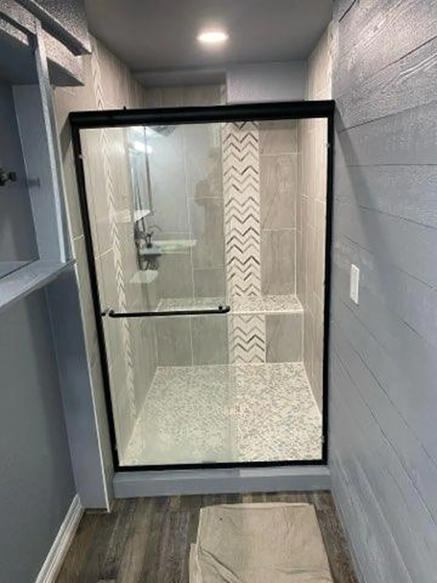 Finished shower with gray tile and black framed glass