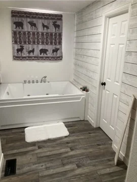 Finished bathroom with tub and wood-look flooring