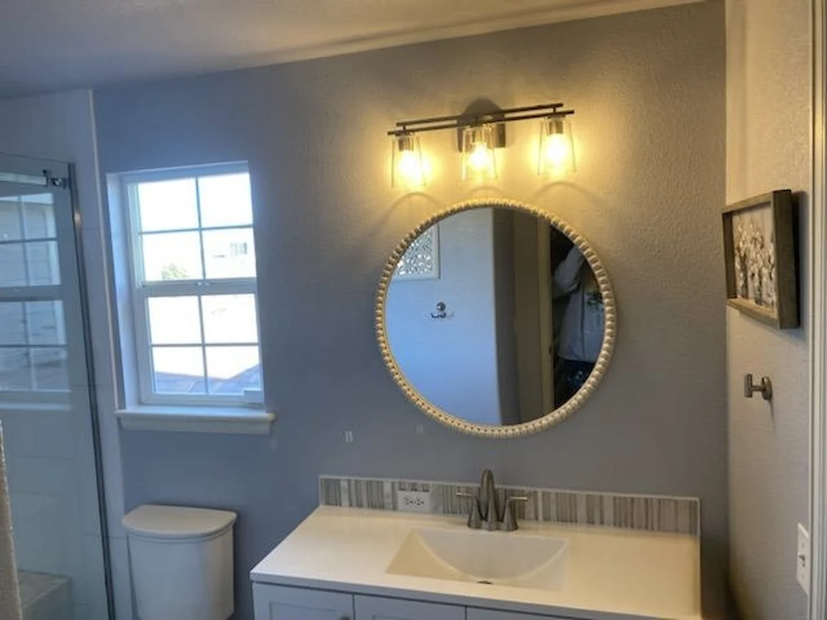 Bathroom vanity with round mirror and updated lighting